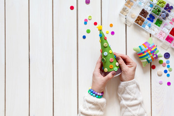 A woman is making a homemade Christmas tree. Decorates it with buttons, threads and yarn.