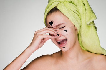 a woman with a towel on her head removes the mask from her face