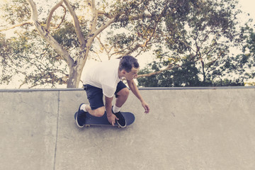 man practicing radical skate board jumping and enjoying tricks and stunts in concrete half pipe...