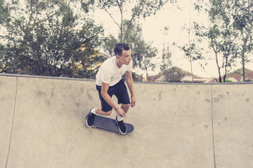 man practicing radical skate board jumping and enjoying tricks and stunts in concrete half pipe skating track in sport and healthy lifestyle