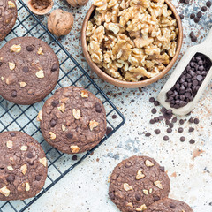 Homemade chocolate cookies with walnuts and chocolate chips on the table and cooling rack, top view, square