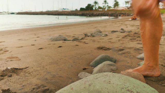 Legs of white man passing by and taking a coin from stone