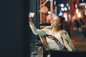 Obraz na płótnie Canvas girl sitting outside a cafe using her phone