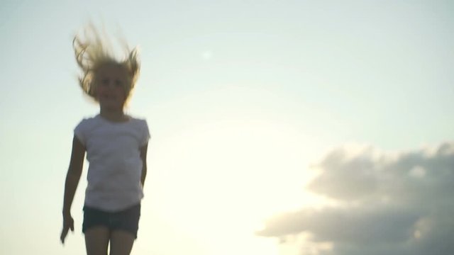 Athletic baby girl at trampoline at sunset rapid slow motion