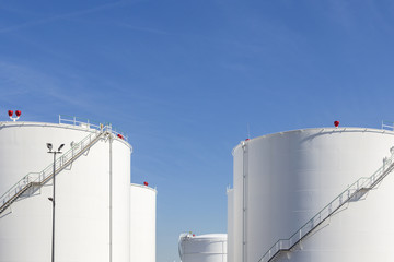 white tanks in tank farm with iron staircase