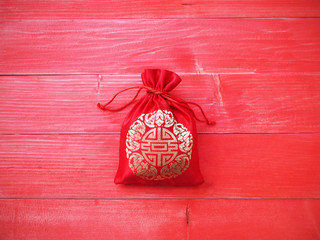 Red silky money bag with string on wood background