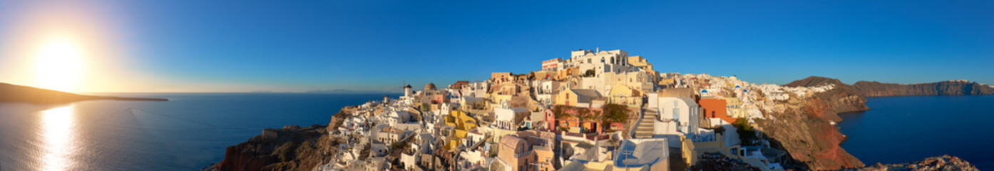 Sunset over Santorini island in Greece. Traditional church, apartments and windmills in Oia village.