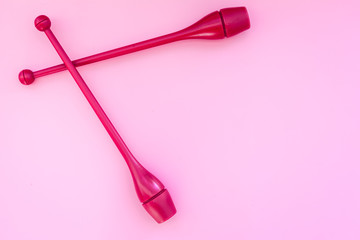 Equipment for rhythmic gymnastics. Clubs on pink background top view copy space