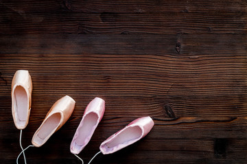 Ballet pointe shoes on dark wooden background top view copy space