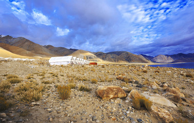 Scenic view of tents lining up in a landscape and beautiful mountain terrain at the background.