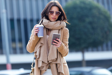 Fototapeta premium Beautiful young woman using her mobile phone in the street.