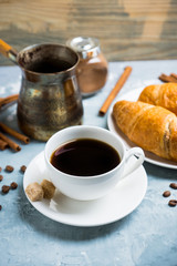 Cup of coffee with croissants on the rustic wooden background. Selective focus. Shallow depth of field.