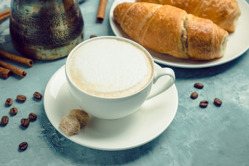 Cup of coffee with croissants on the rustic wooden background. Selective focus. Shallow depth of field.