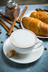 Cup of coffee with croissants on the rustic wooden background. Selective focus. Shallow depth of field.