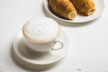 Cup of coffee with croissants on the rustic wooden background. Selective focus. Shallow depth of field.