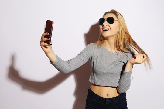 Pretty hipster girl making selfie over white background.