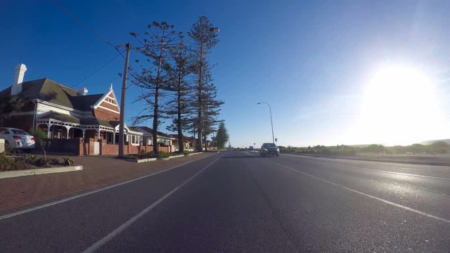 Vehicle POV driving along seaside esplanade with sunset over ocean. Taken at Semaphore Largs Bay, South Australia.