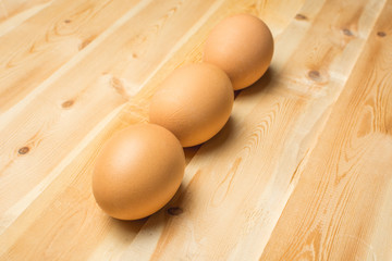Three chicken eggs lie on a wooden board