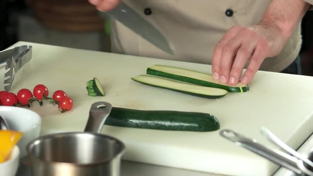 Hands of chef cutting vegetable. Fresh sliced zucchini.