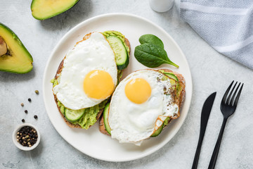 Egg and avocado breakfast toast on white plate. Table top view. Healthy eating dieting concept