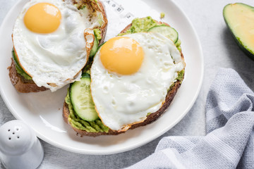Egg and avocado breakfast toast on white plate. Closeup view. Healthy eating dieting concept