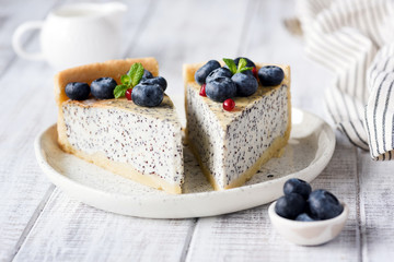 Cheesecake with poppy and blueberries. Homemade poppy pie on white plate decorated with blueberries and mint. Closeup view