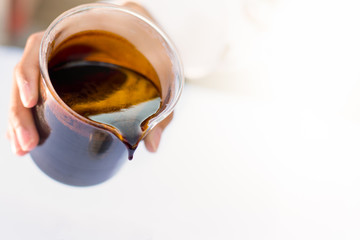 Molasses sugarcane on beaker. Droping molasses with hands. Molasses is the final product from the sugarcane extraction process of sugar factory. industrial concepts.
