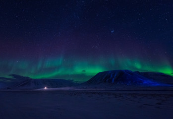 The polar arctic Northern lights aurora borealis sky star in Norway Svalbard in Longyearbyen city town mountains