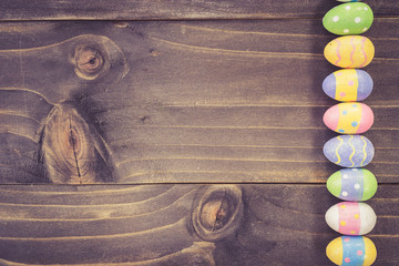 Colorful easter eggs on plank wooden background with space.