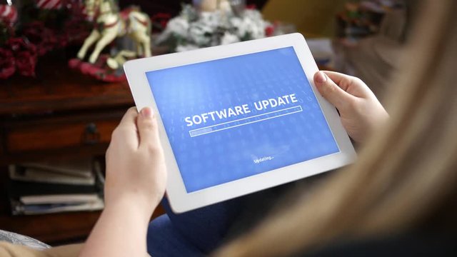 Woman uses tablet to update her software in living room