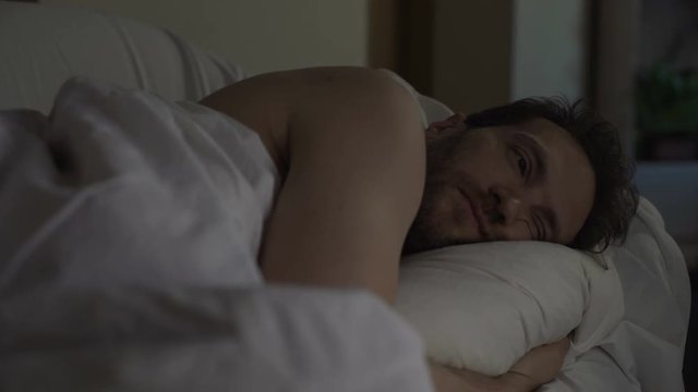 Annoyed man tossing and turning in bed unable to fall asleep, noisy neighbors