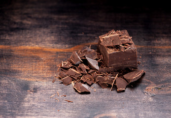 Pieces and chopped chocolate on a dark wooden background