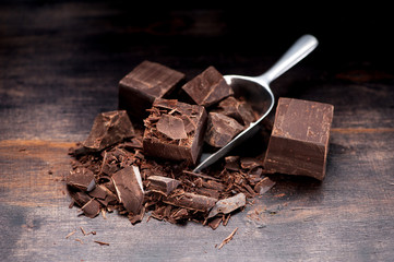 Pieces and chopped chocolate on a dark wooden background