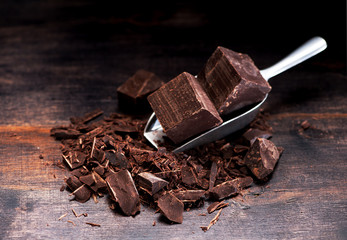 Pieces and chopped chocolate on a dark wooden background