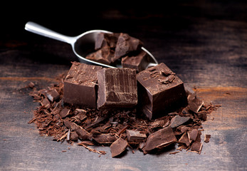Dark chocolate in a metal scoop and on a table