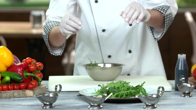 Chef preparing salad, herb. Cooking table, fresh arugula.