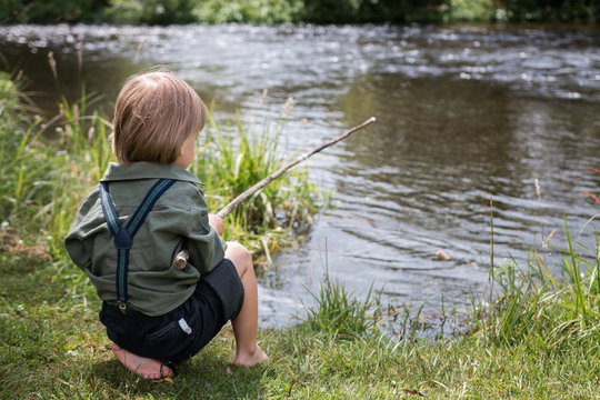 Little boy with old-fashioned fishing rod on a river shore Stock Photo