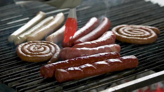 Brush covering sausages with oil. Grilling food close up.