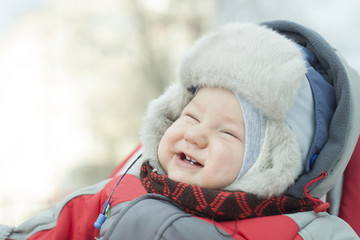 portrait of a laughing little boy in a fur hat with a fur hat for a winter walk