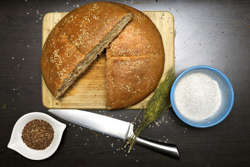 Home made integral bread with flax seeds, integral flour, dill and knife on wooden table