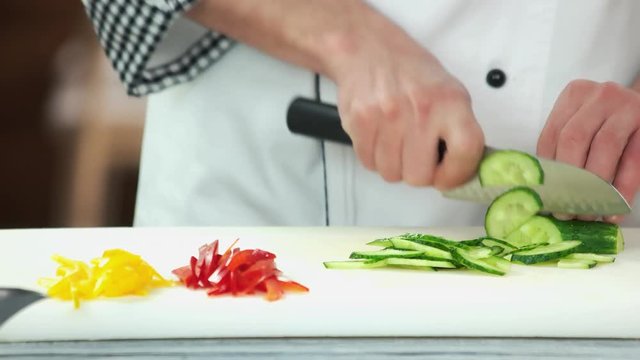 Hands of chef cutting cucumber. Pieces of vegetables.