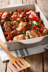 rabbit meat baked with mushrooms, onions and bell peppers close-up in a baking dish. vertical
