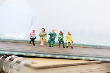 Miniature people : Business team sitting on book and having a coffee break. Image use for business concept.