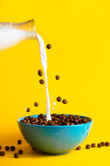 Chocolate breakfast cereals and plant milk poured into the bowl, concept of breakfast and morning,...