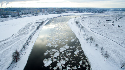 Fototapeta na wymiar Ice swims in the river. Winter landscape photographed from above near the city. Top view. Nature and abstract background