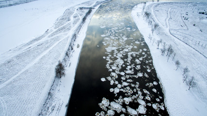 Ice swims in the river. Winter landscape photographed from above. Top view. Nature and abstract background