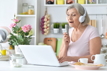 Obraz na płótnie Canvas Portrait of beautiful senior woman singing with microphone
