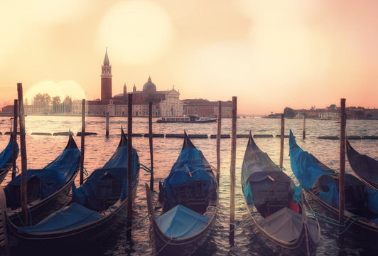 Venice classic sunrise view with gondolas on the waves and bokeh lights