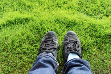 legs in black sneakers and blue jeans on the green grass