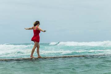 Fototapeta na wymiar Young Girl Walking Challenge Tidal Pool next to ocean waves
